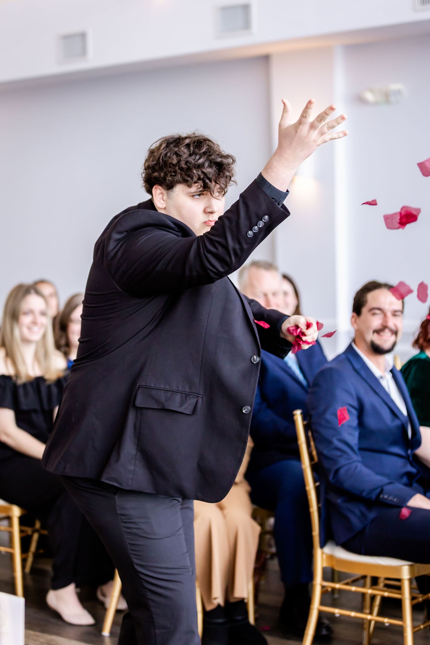 Wedding guests enjoying festivities with rose petals in an indoor venue.