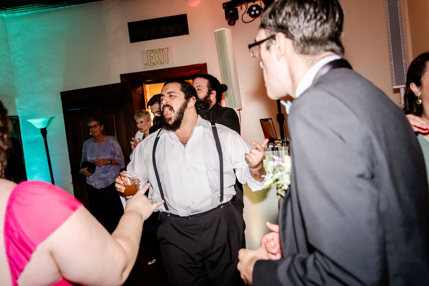 Wedding reception dance party with lively guests dancing under colorful lights.