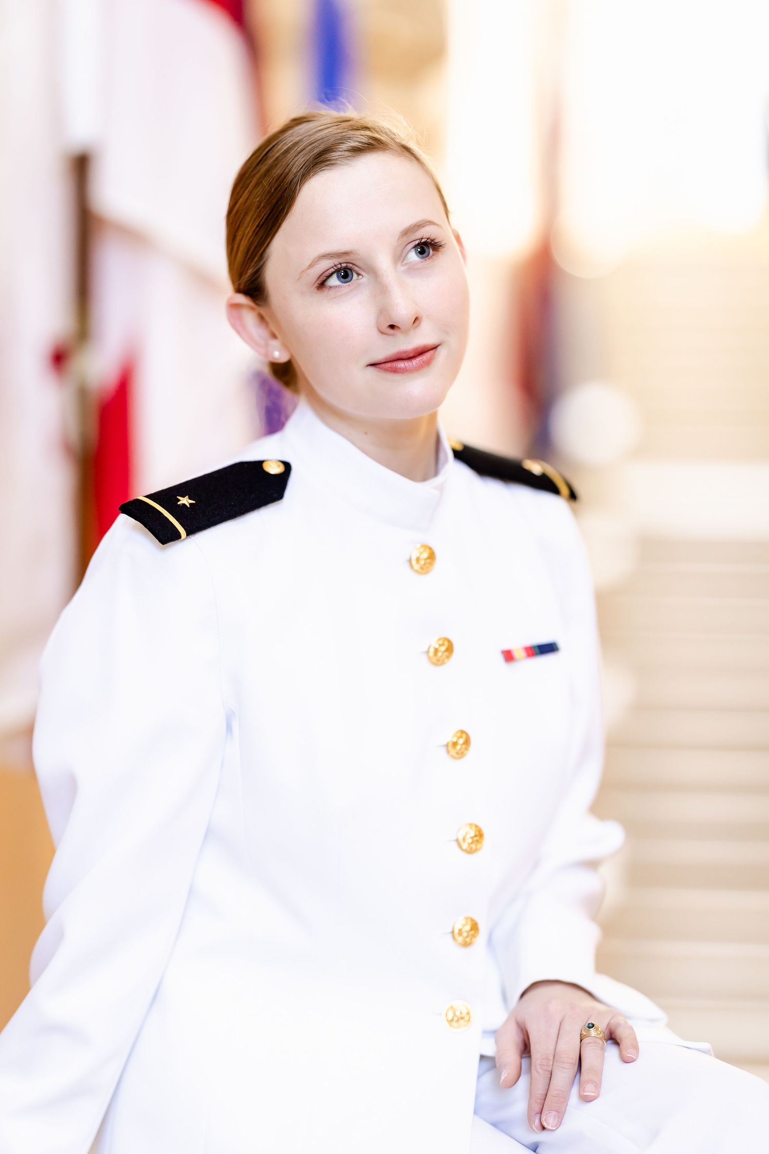 Military officer in crisp white dress uniform with gold buttons poses for portrait.