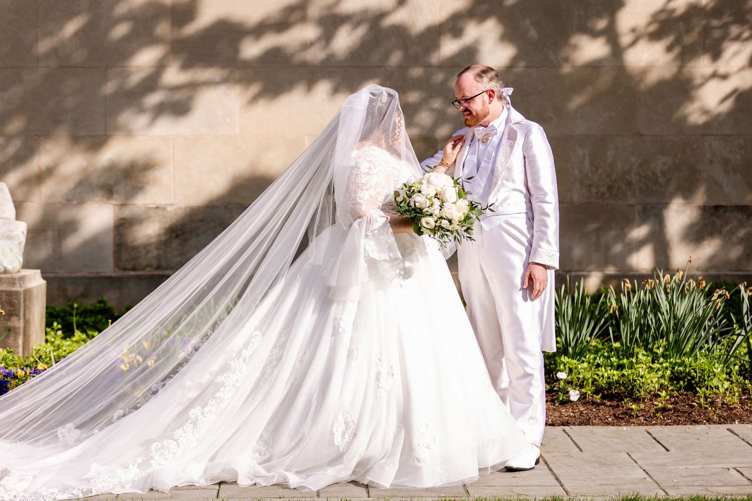 Couple shares romantic moment in garden setting with dramatic tree shadows.