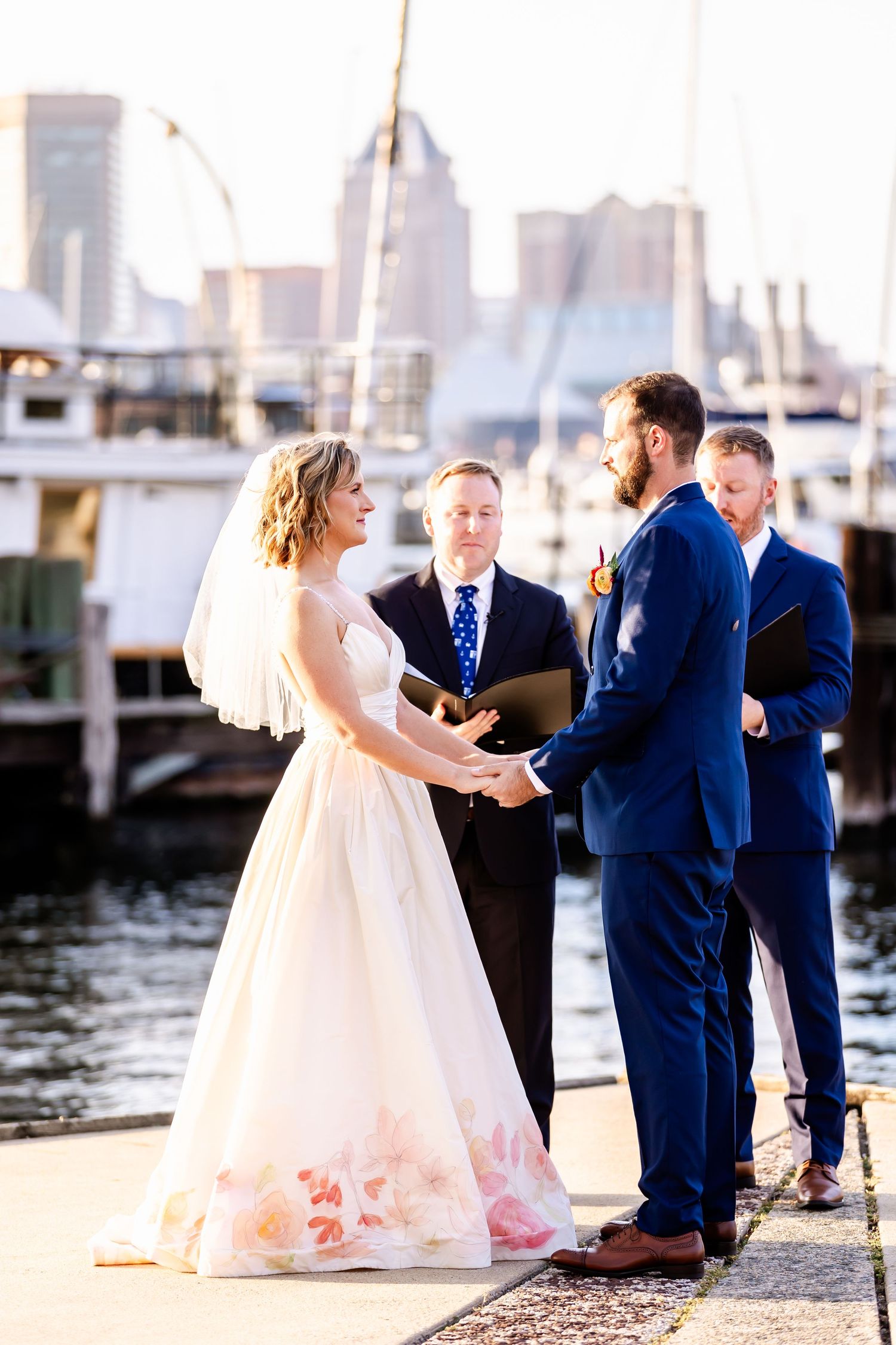 A waterfront wedding ceremony at a marina with city skyline views in the background.