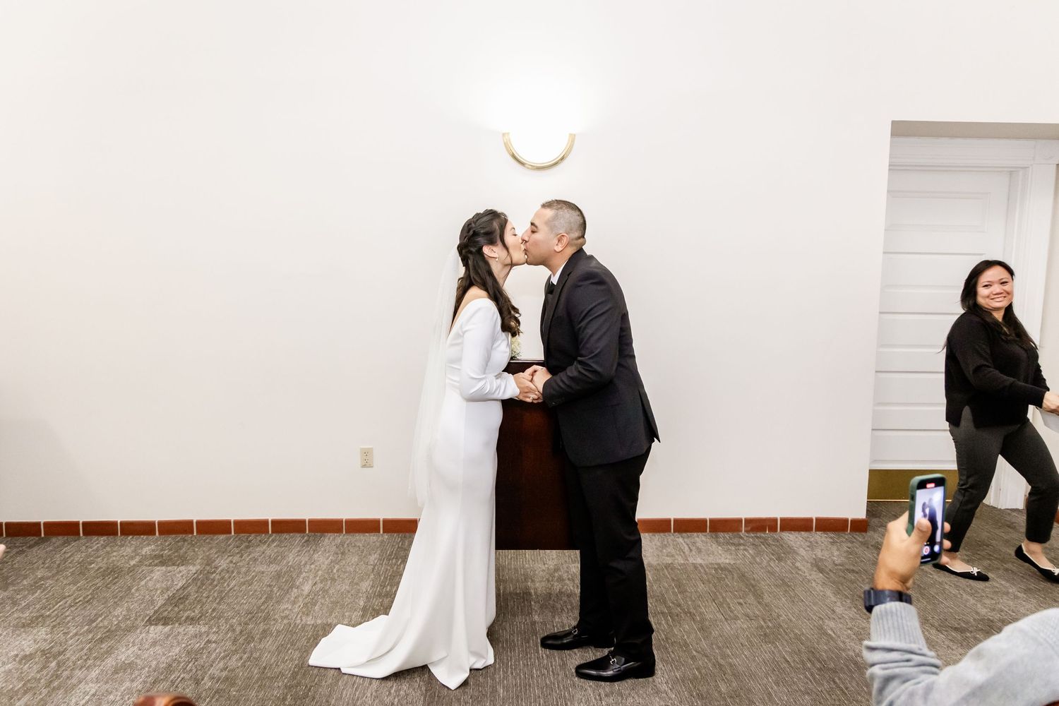 Couple shares their first kiss as newlyweds during an indoor wedding ceremony.