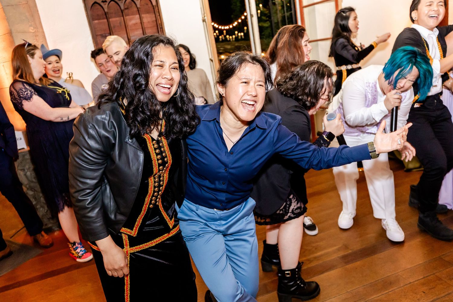 Two guests dancing with excitement and laughter at an indoor celebration.