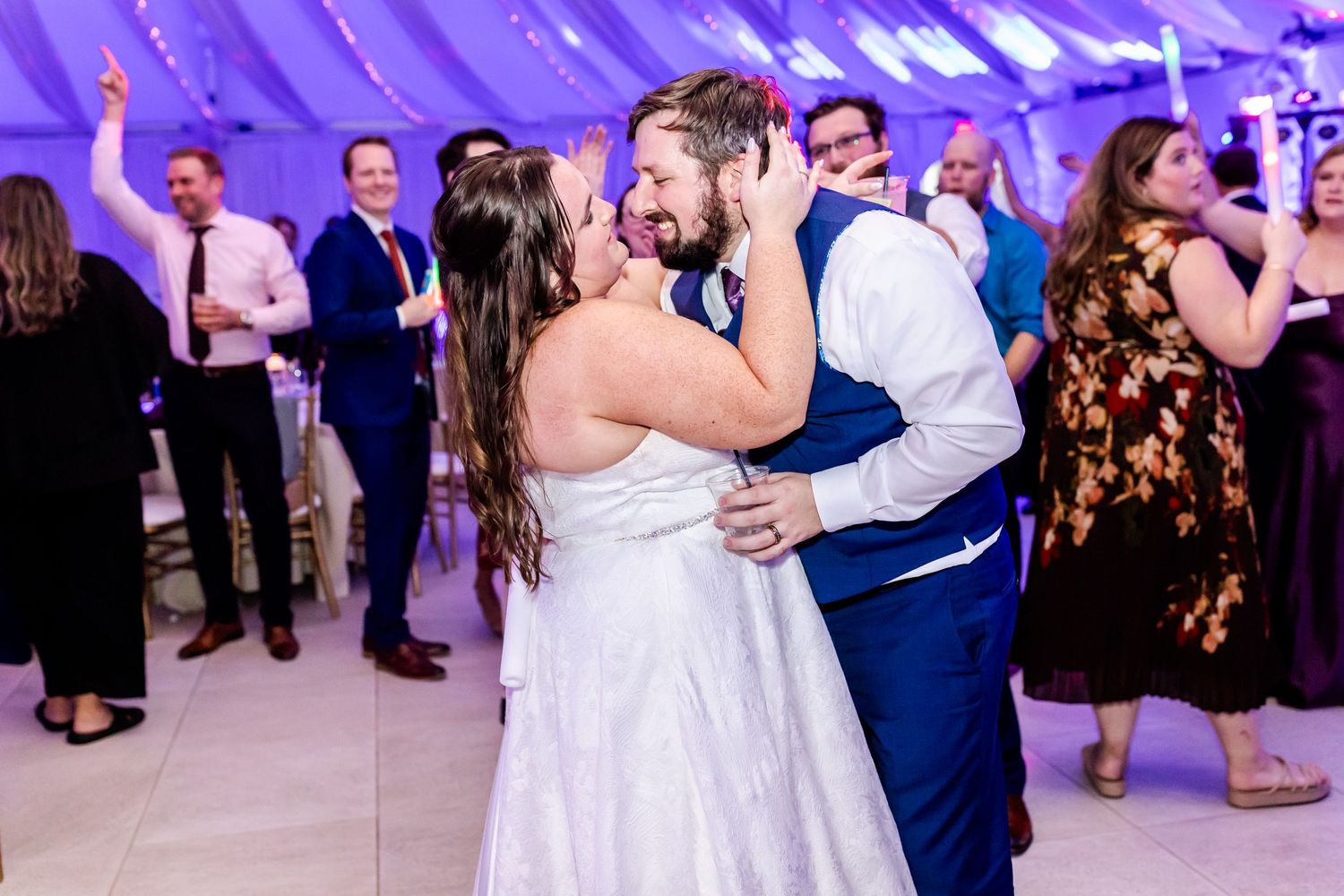 Couple sharing romantic dance moment under purple-lit draped ceiling.