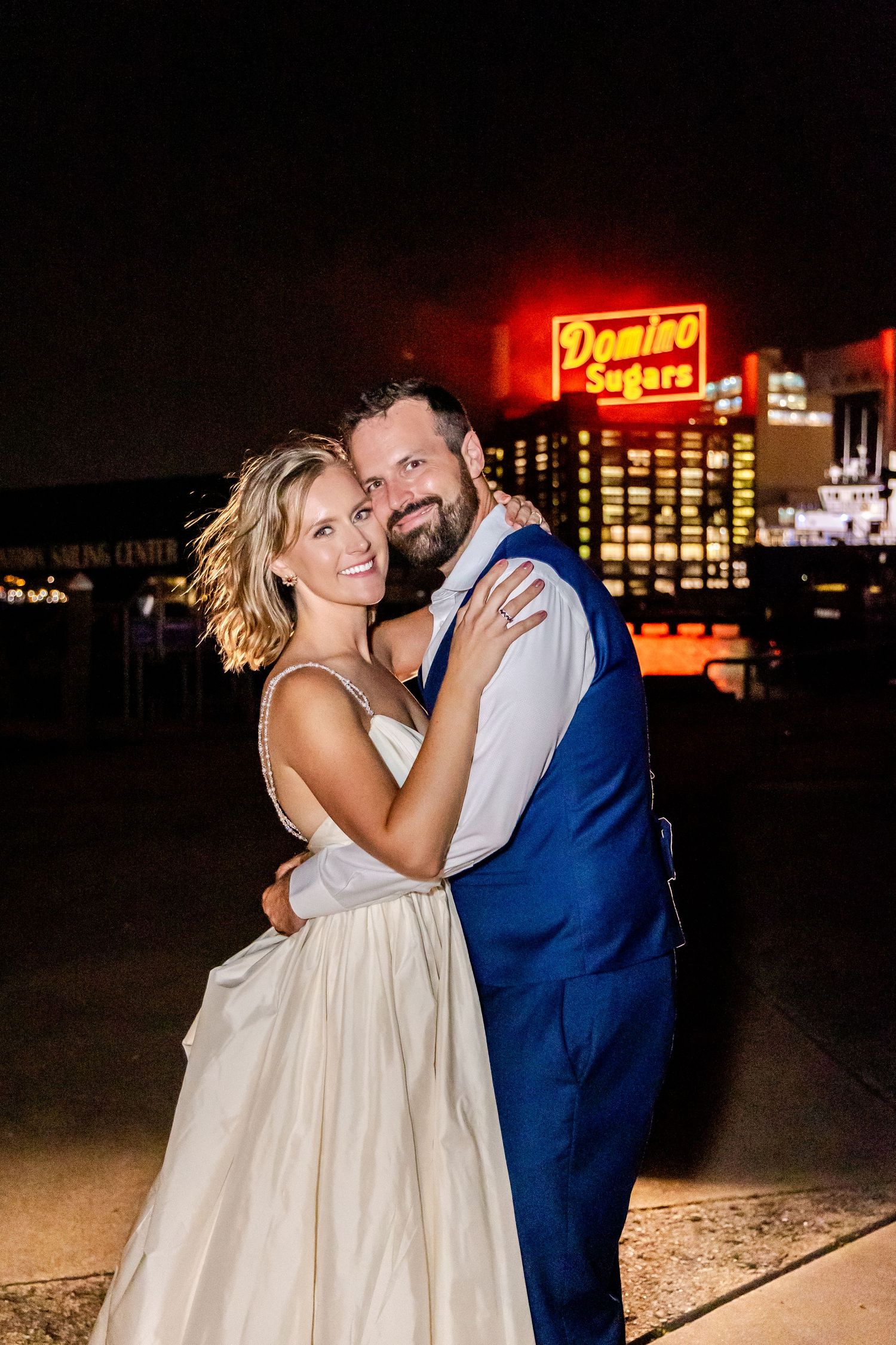 A couple shares a romantic dance at night with illuminated signs glowing in the background.