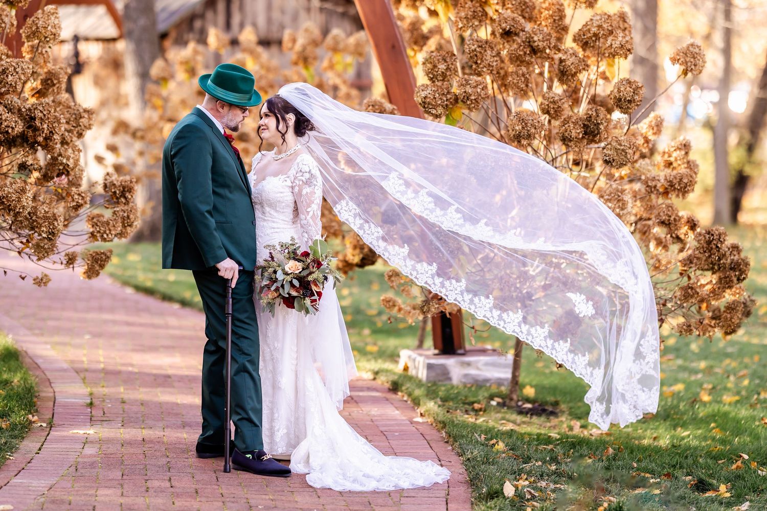A long white lace veil flows gracefully in the wind during an outdoor autumn wedding photoshoot.