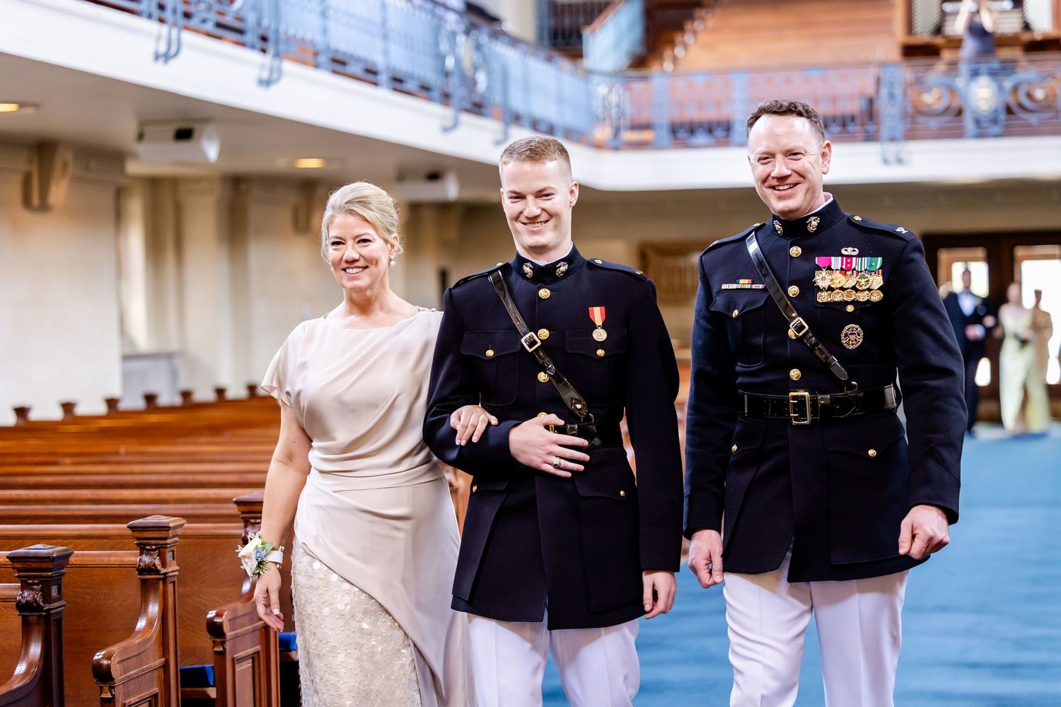 Wedding party members walk and celebrate together in a church sanctuary with blue pews.