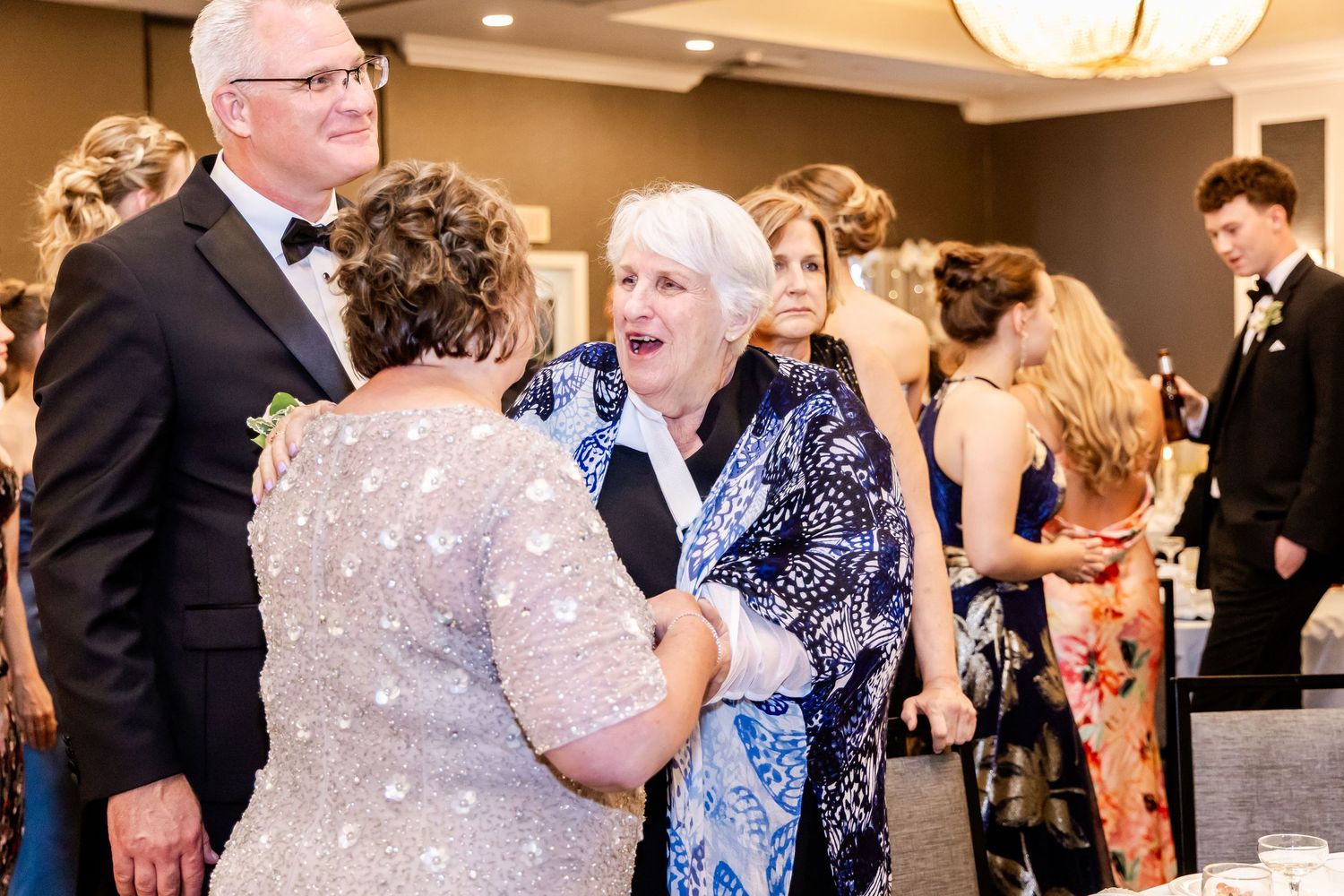 Wedding guests dancing and celebrating at an elegant indoor reception with warm lighting.