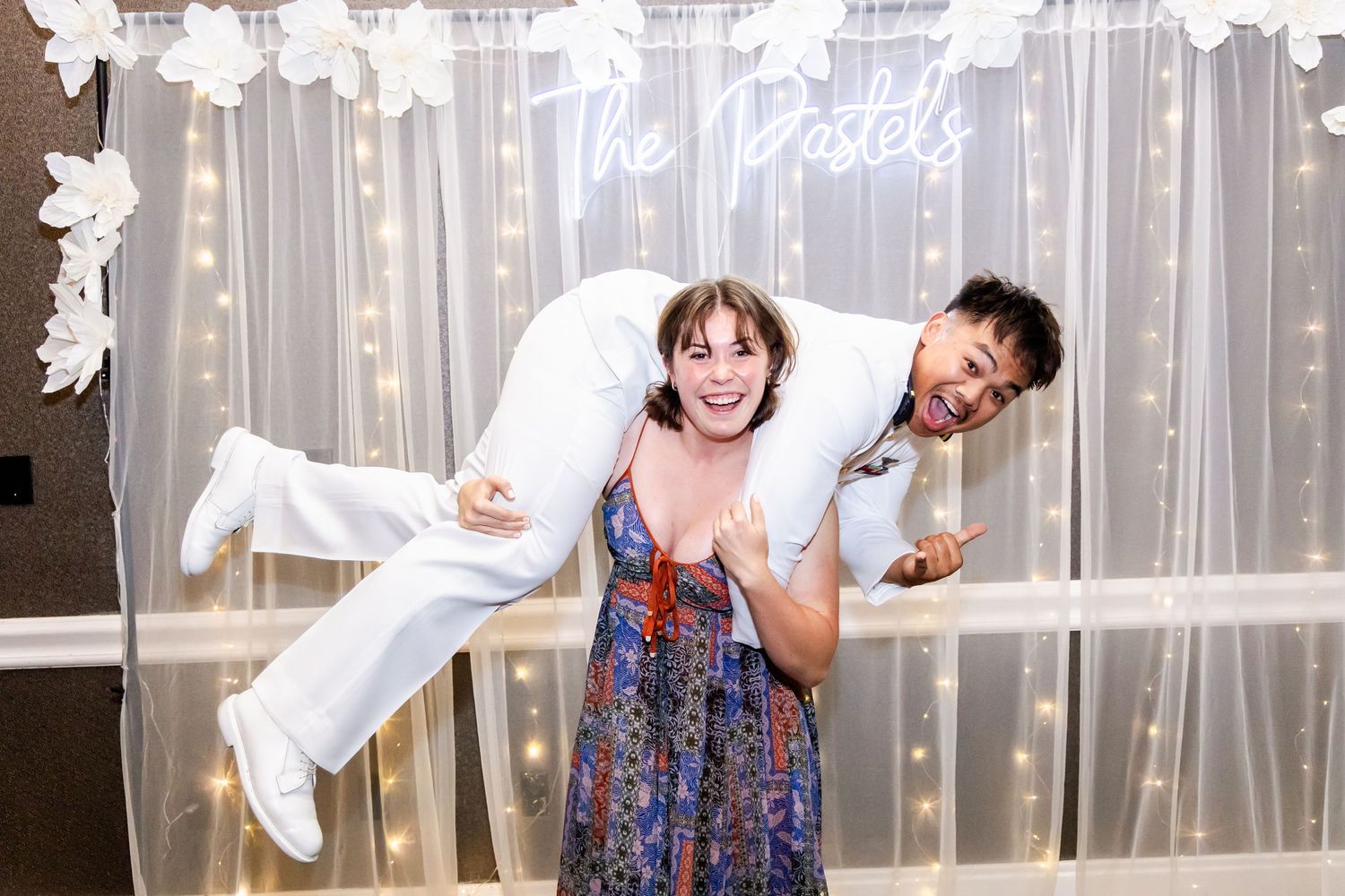 Wedding party celebrates with energetic dance moves on reception dance floor.