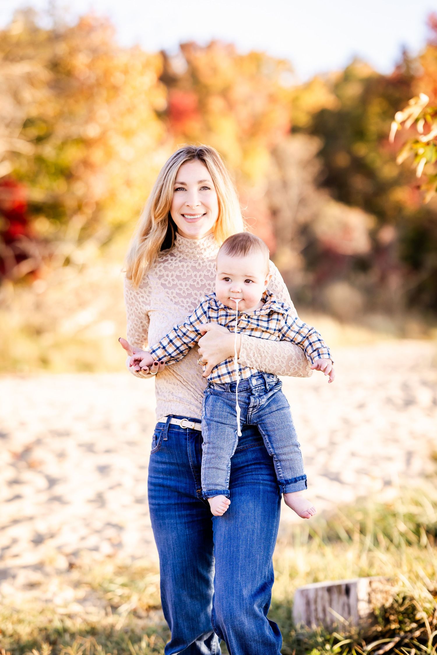 Parent and child playing together outdoors on a sunny autumn day with golden foliage in the background.
