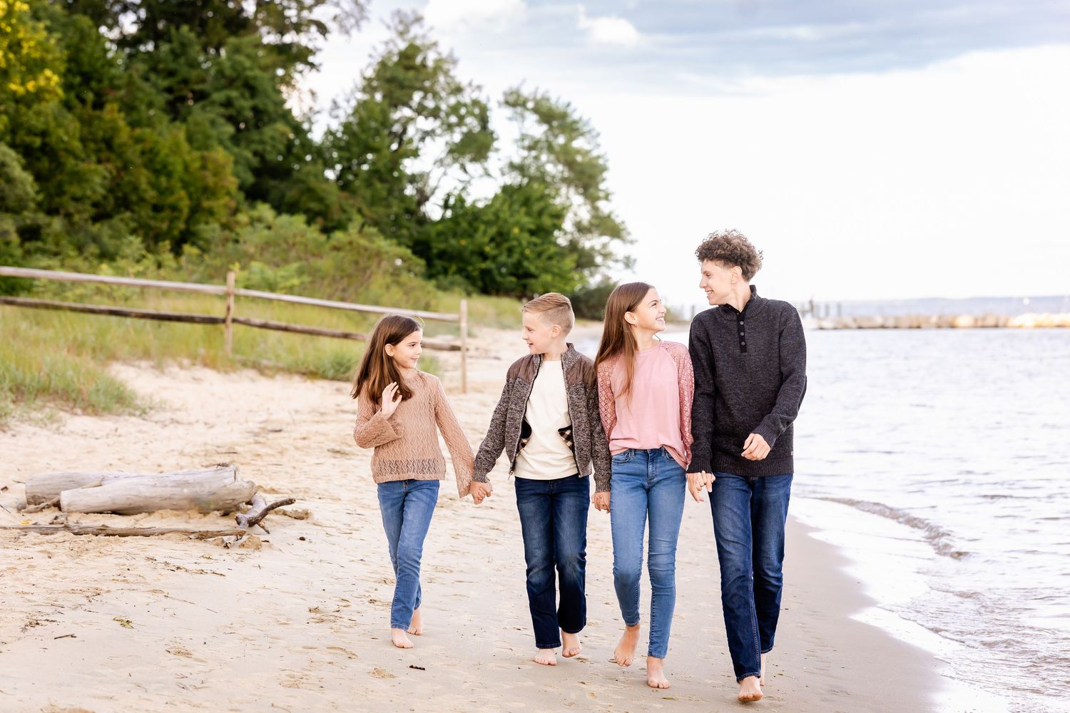 Group of people walking together along a sandy beach shoreline on a cloudy day.