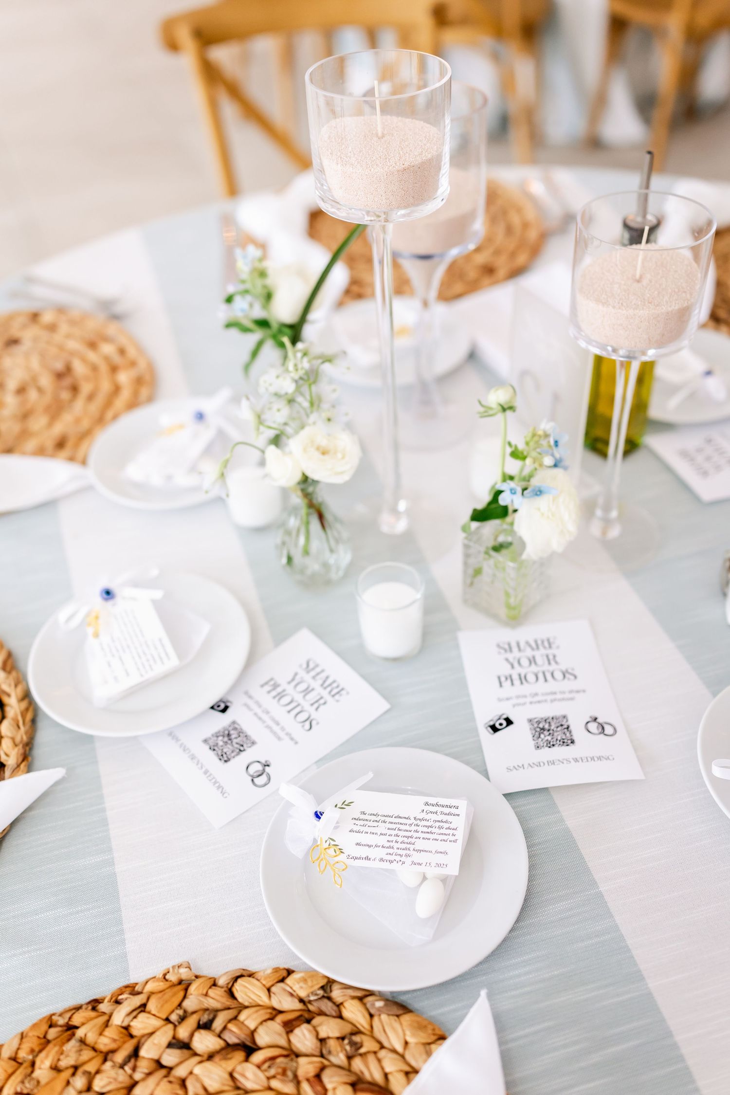 Elegant table settings with white floral centerpieces and place cards at a wedding reception.