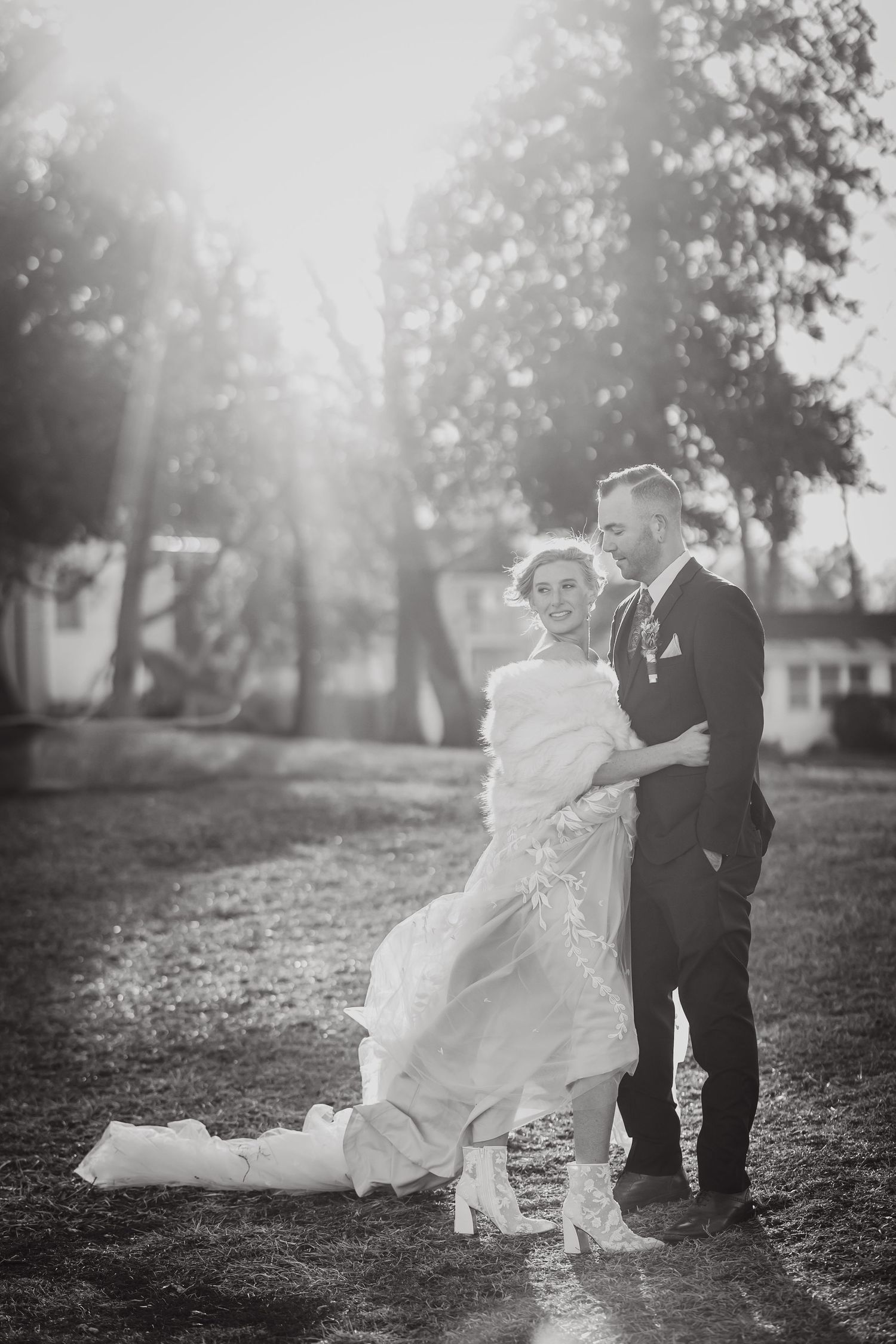 A black and white wedding portrait of a couple outdoors in dramatic lighting.