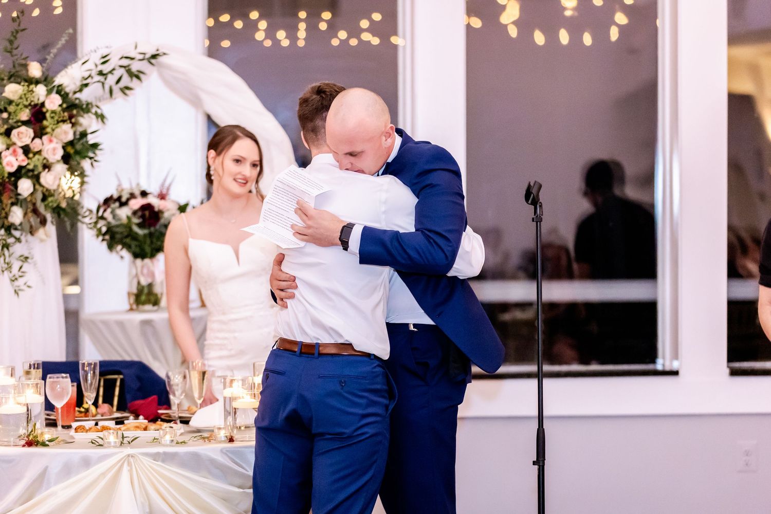 Wedding reception guests dancing and celebrating in a brightly lit indoor venue.