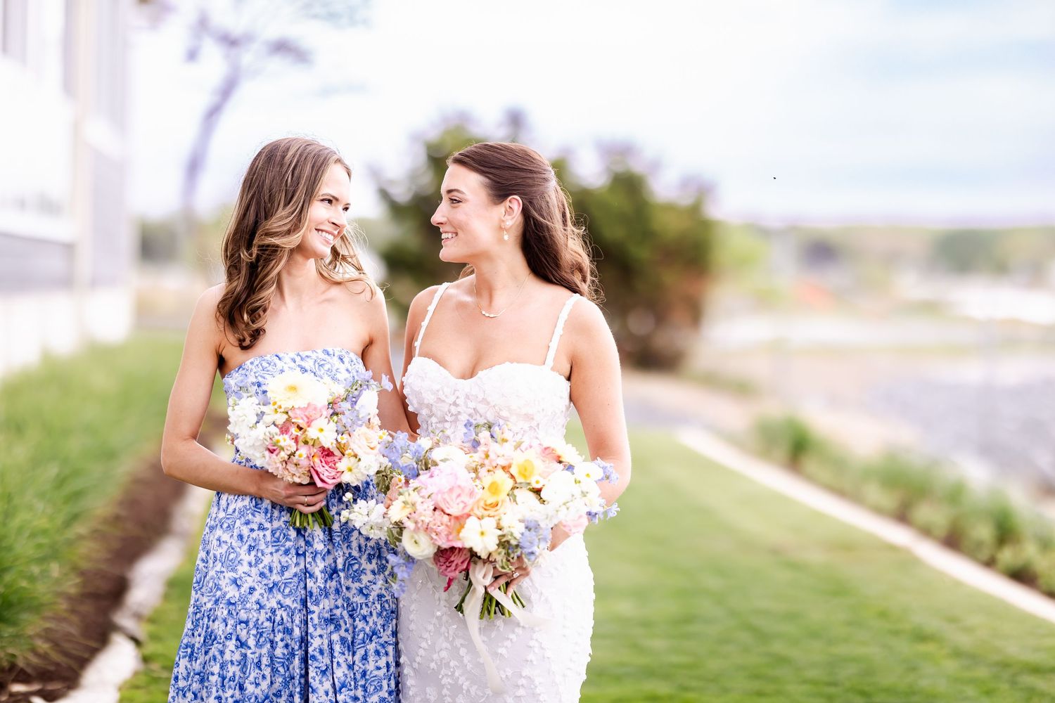 Wedding party members holding bouquets outdoors on a sunny day.