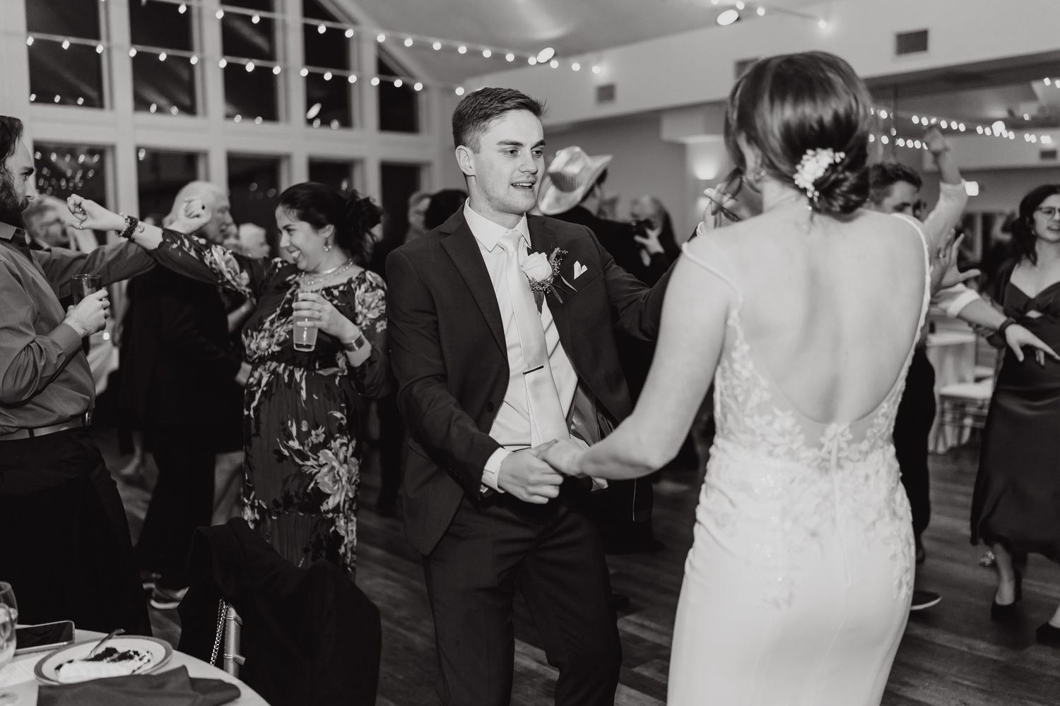 Black and white photo of wedding guests dancing at an indoor reception.
