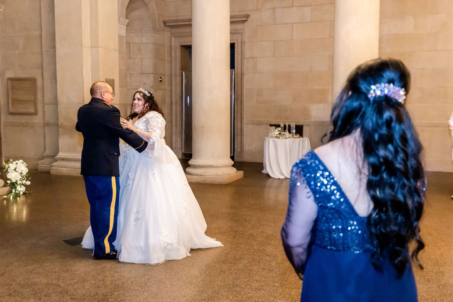 Wedding couple dances in a historic venue while guests look on.