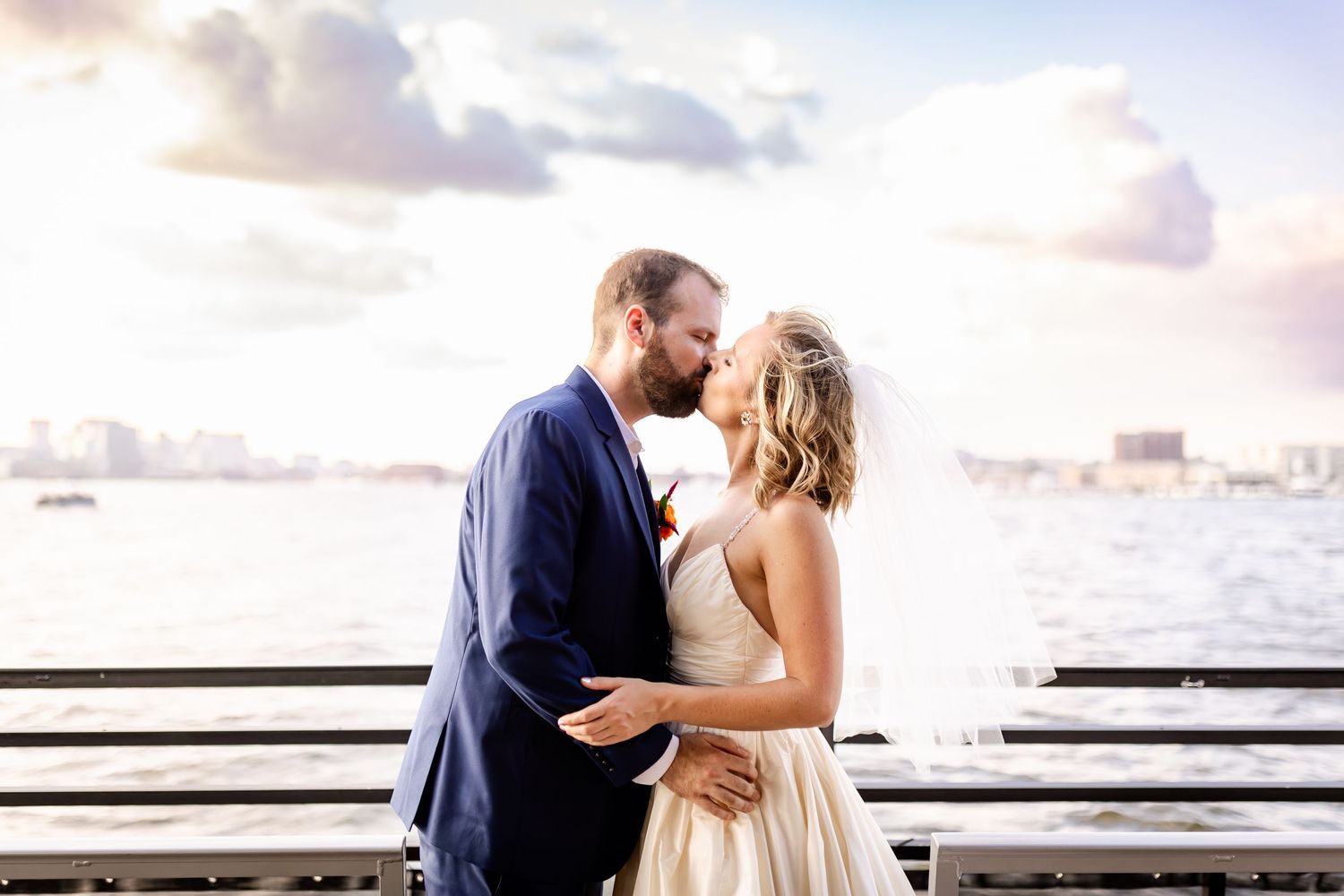 A romantic moment captured at sunset by the waterfront with boats in the background.