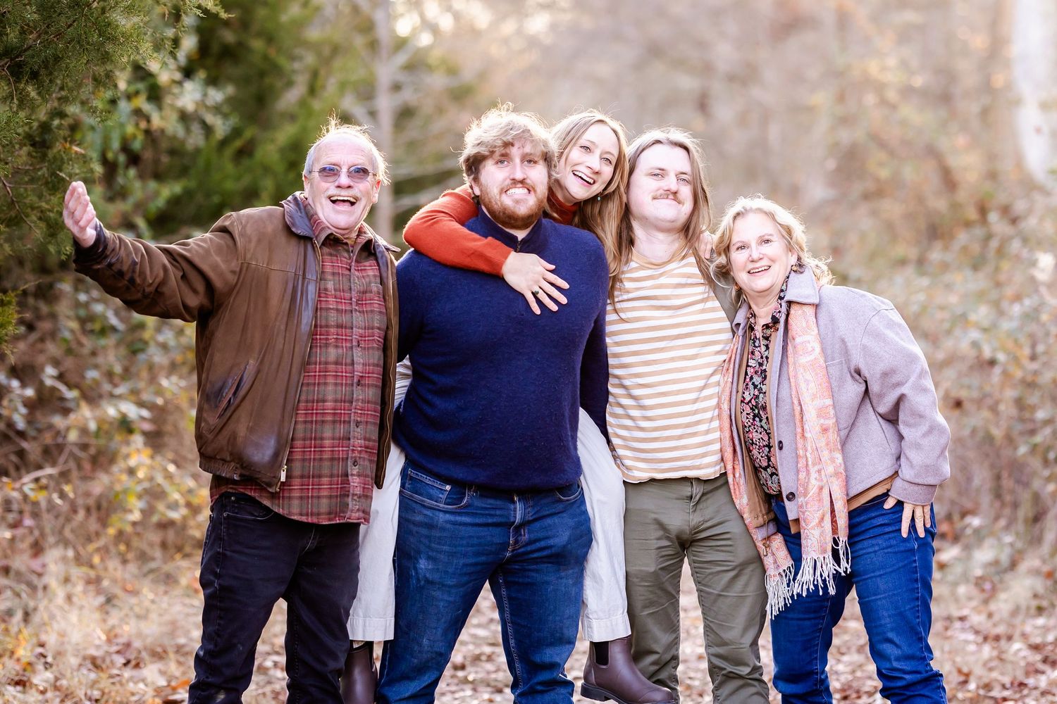 Multi-generational group poses together outdoors on an autumn day wearing casual clothing.