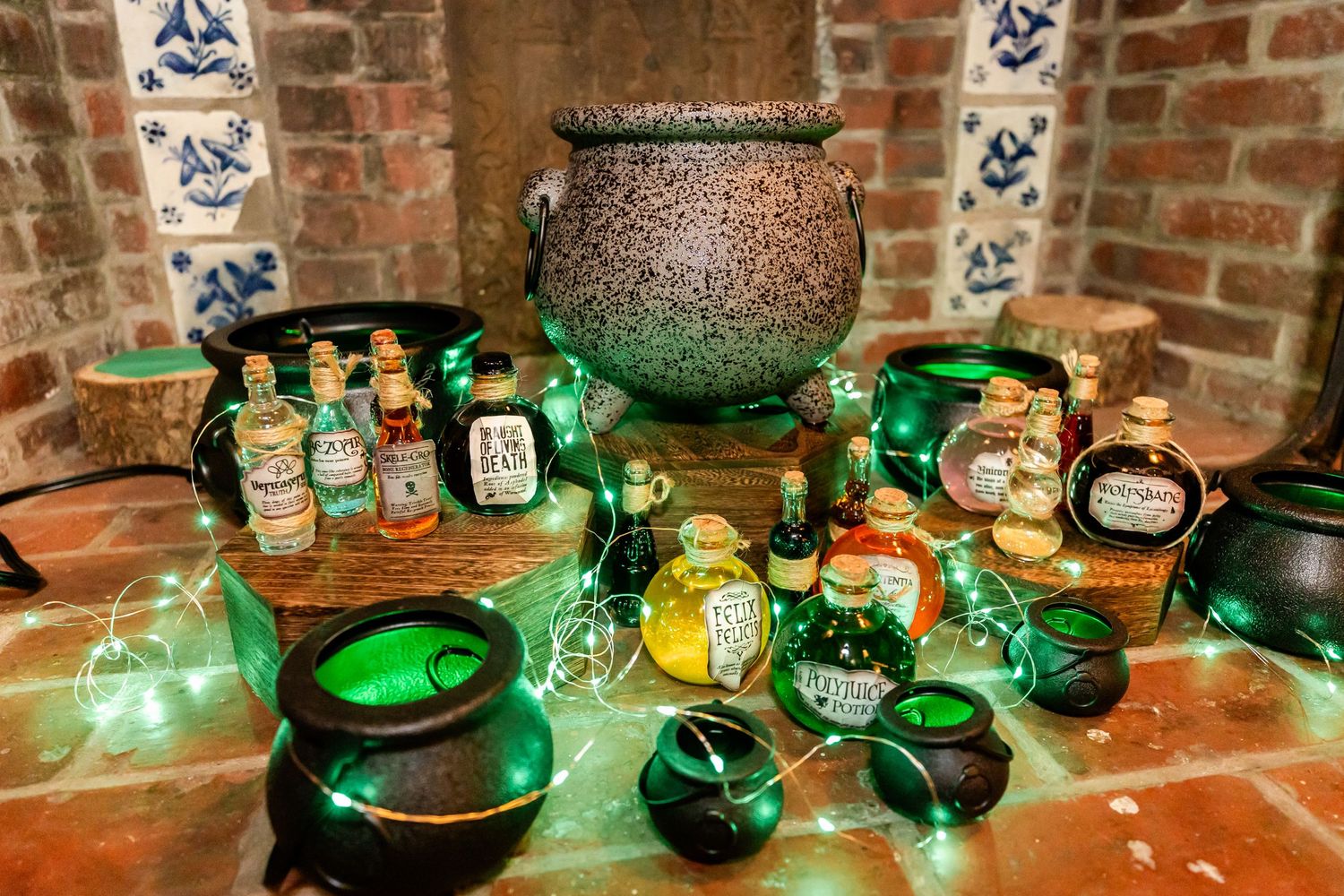 Magical potion display with glowing green bottles and cauldrons on brick surface.