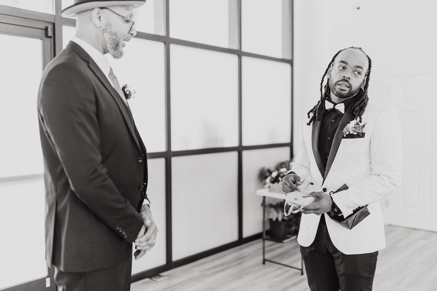 Black and white candid wedding preparation moment between two people.
