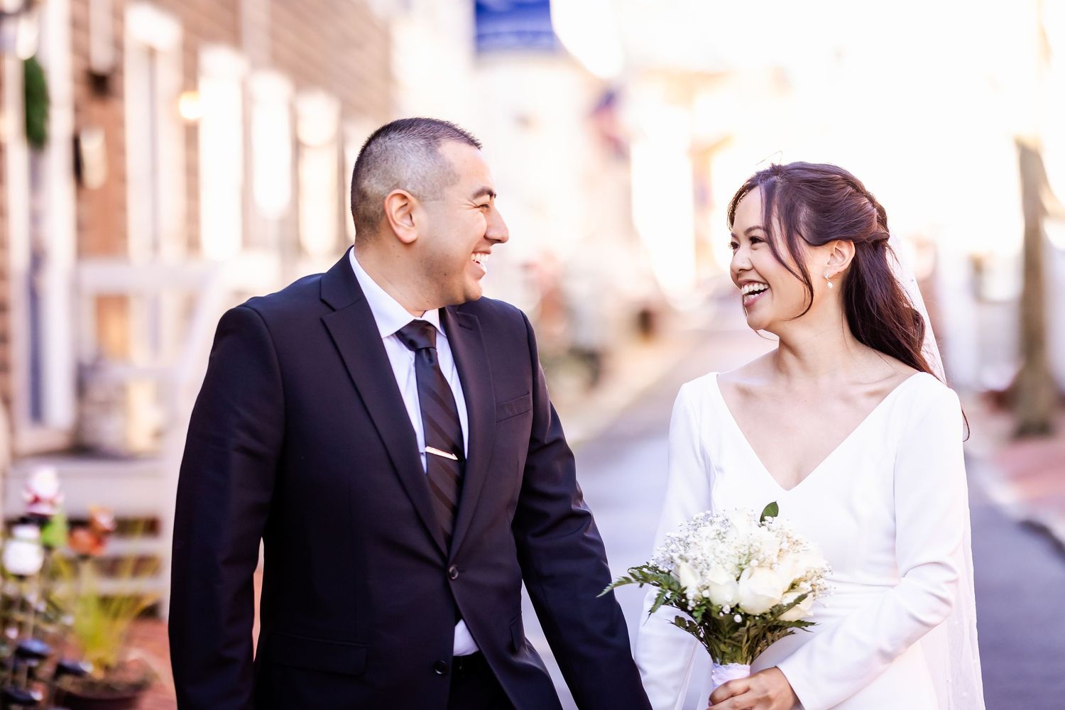 Happy newlyweds share a joyful moment together on a sunlit street.