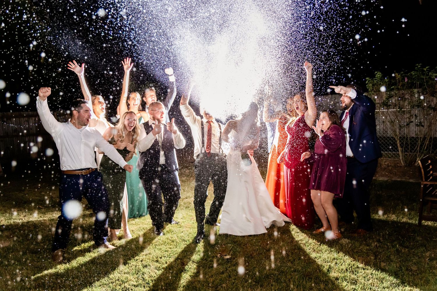 Wedding guests dancing and celebrating under twinkling lights at an outdoor evening reception.