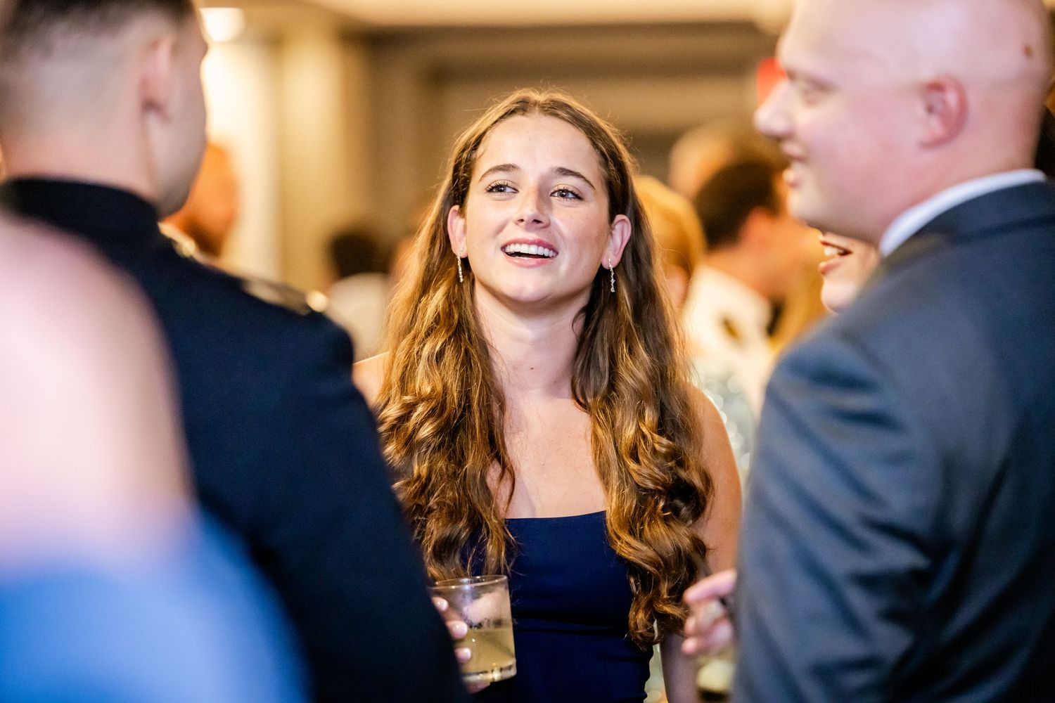 Wedding guests enjoying conversation and laughter during an indoor evening reception.