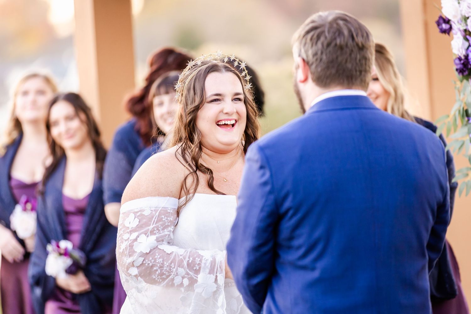 A bride shares a heartfelt laugh during an emotional moment at her outdoor wedding ceremony.