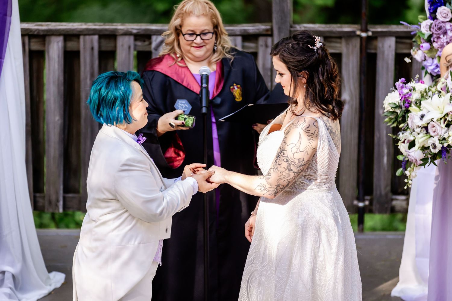 A wedding ceremony officiated under a decorated wooden pergola with purple and white drapery.