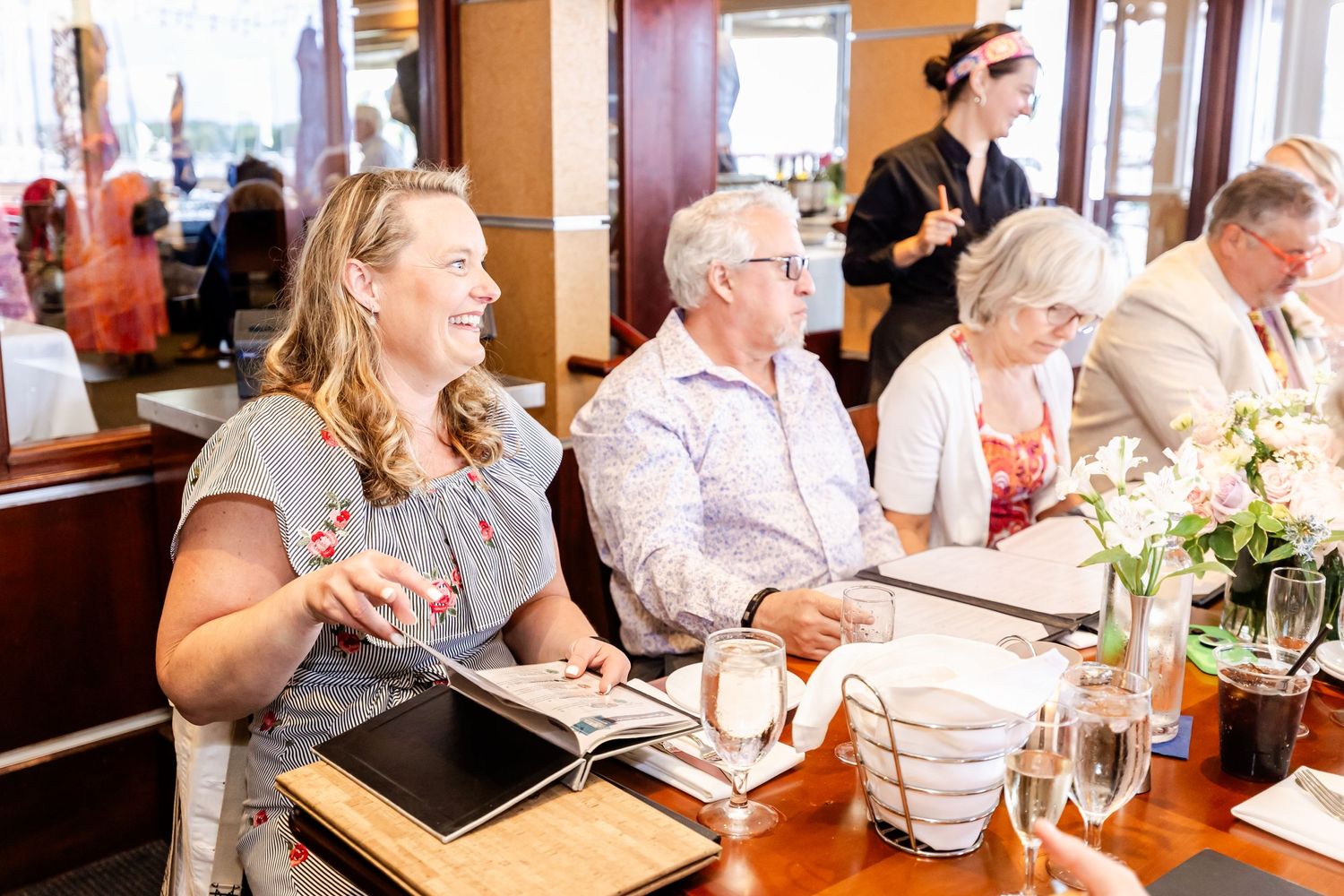People gathered around a restaurant table for a celebratory meal with floral decorations.