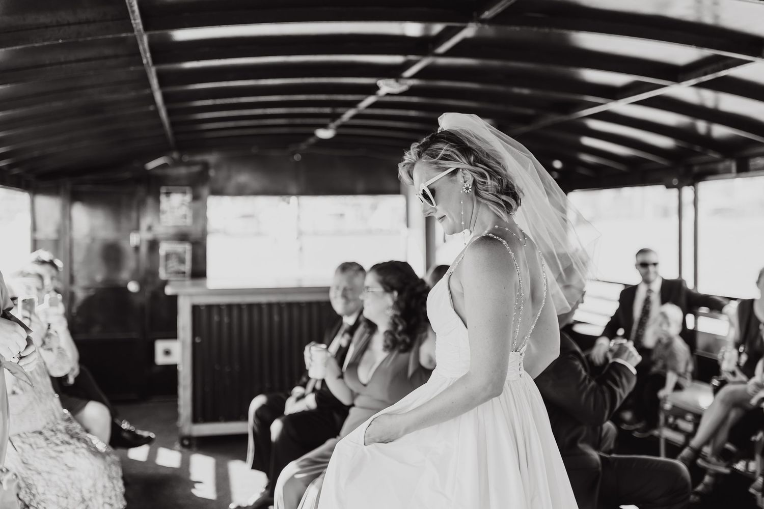 Black and white candid wedding moment captured inside covered waterfront venue.