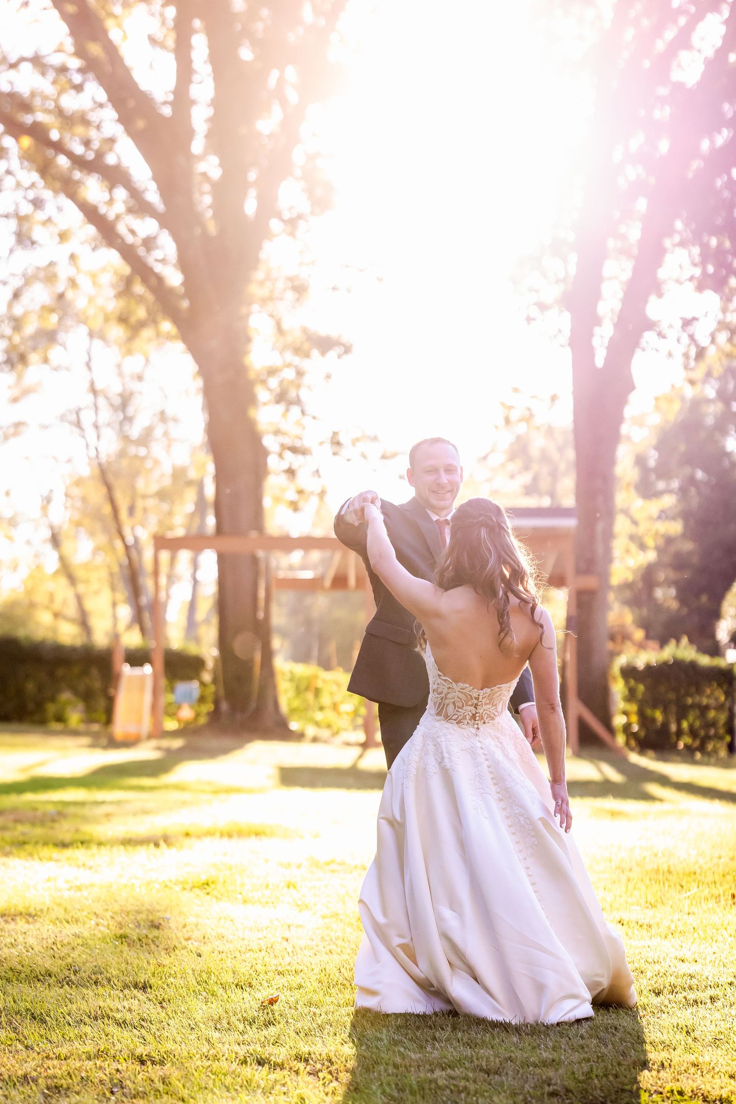 Newlyweds dance together in a sunlit garden during golden hour.