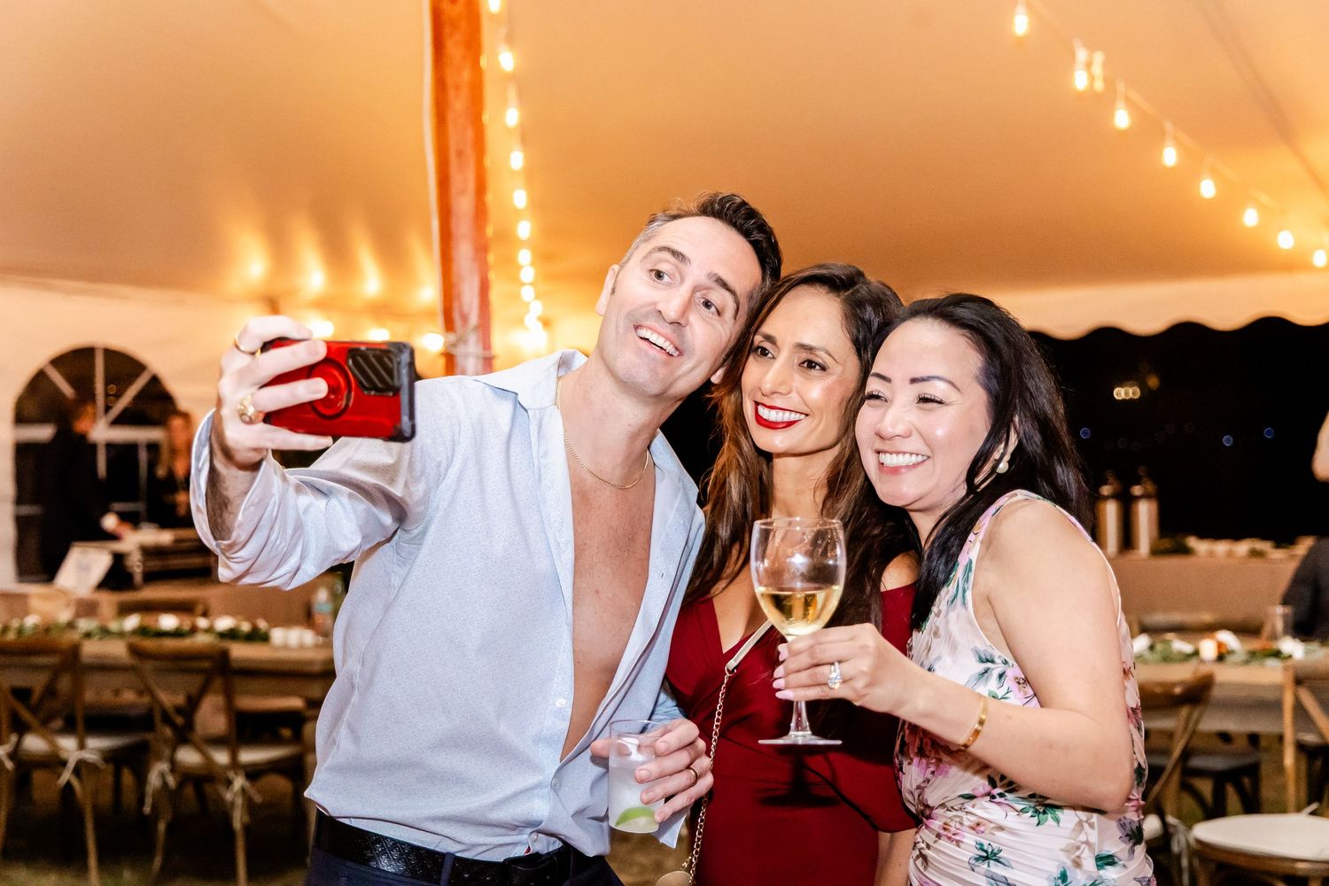 Wedding reception celebration under a tent with string lights creating warm ambiance.