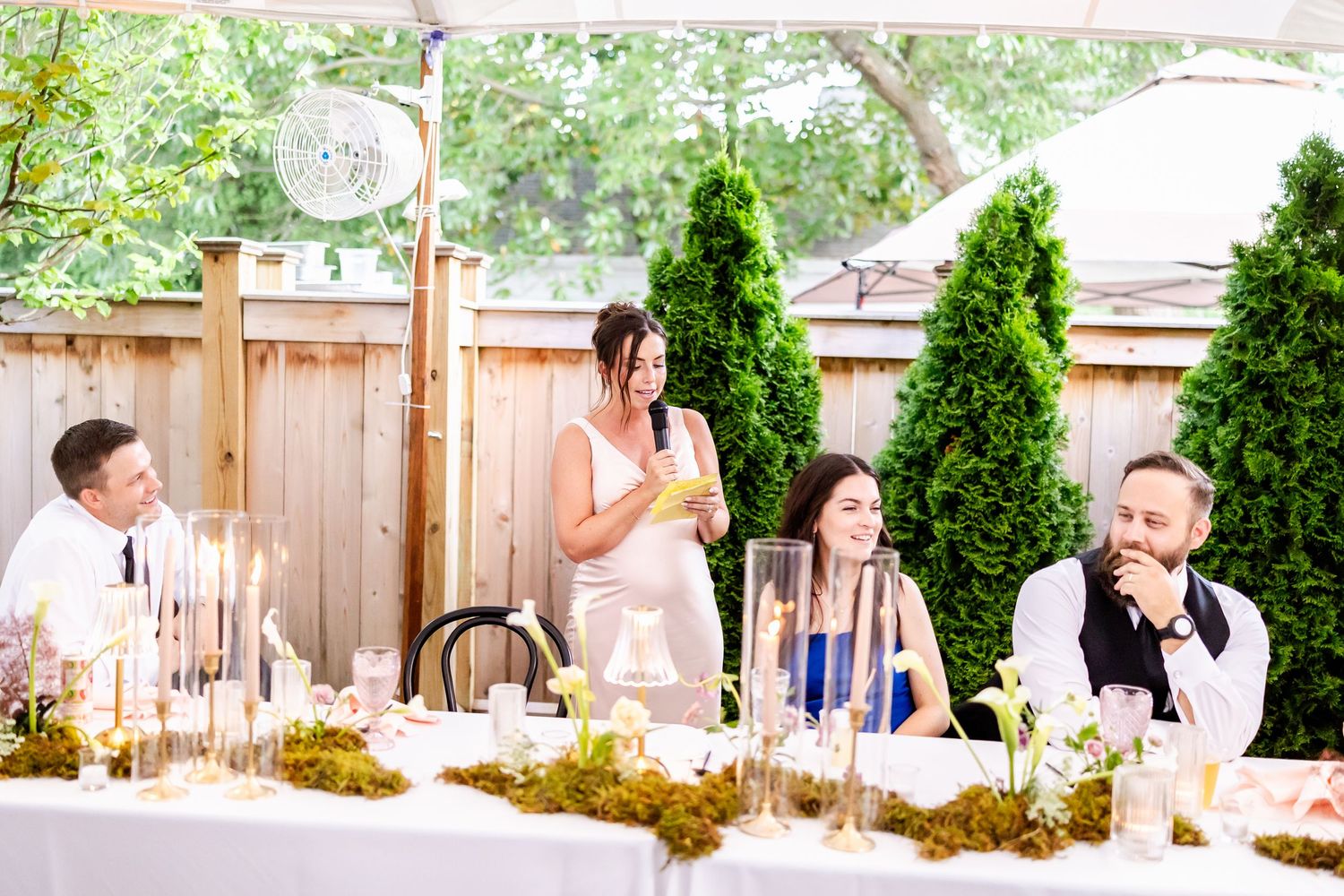Garden party reception with guests mingling under string lights and greenery.