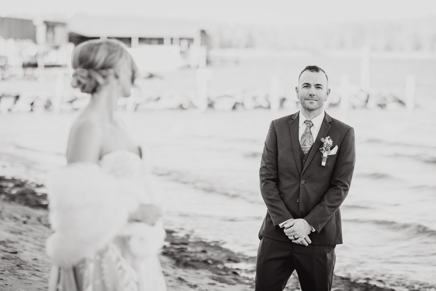 A coastal beach wedding moment captured in black and white as couple meets for their first look by the ocean.