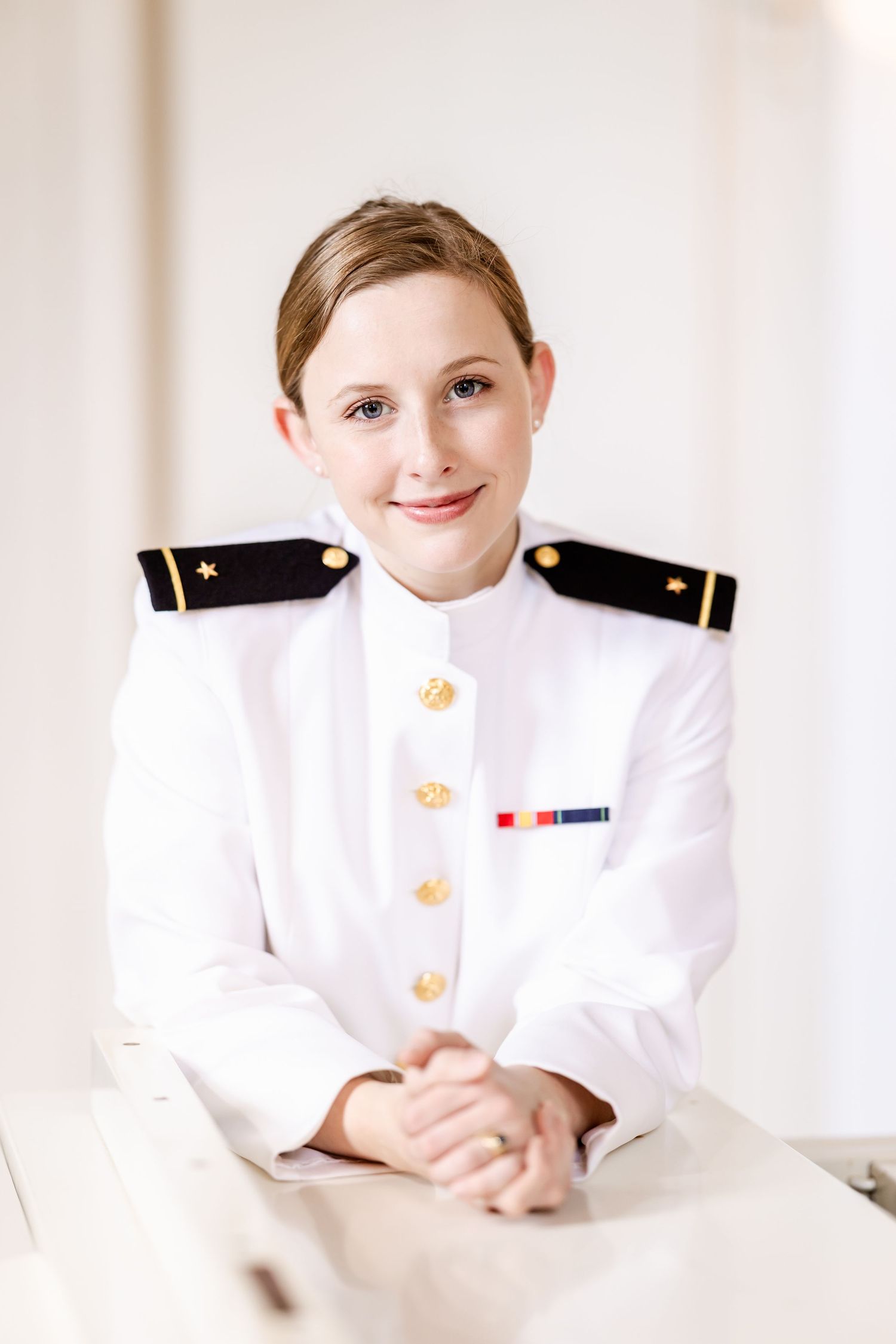 Service member in white military dress uniform poses for formal portrait.