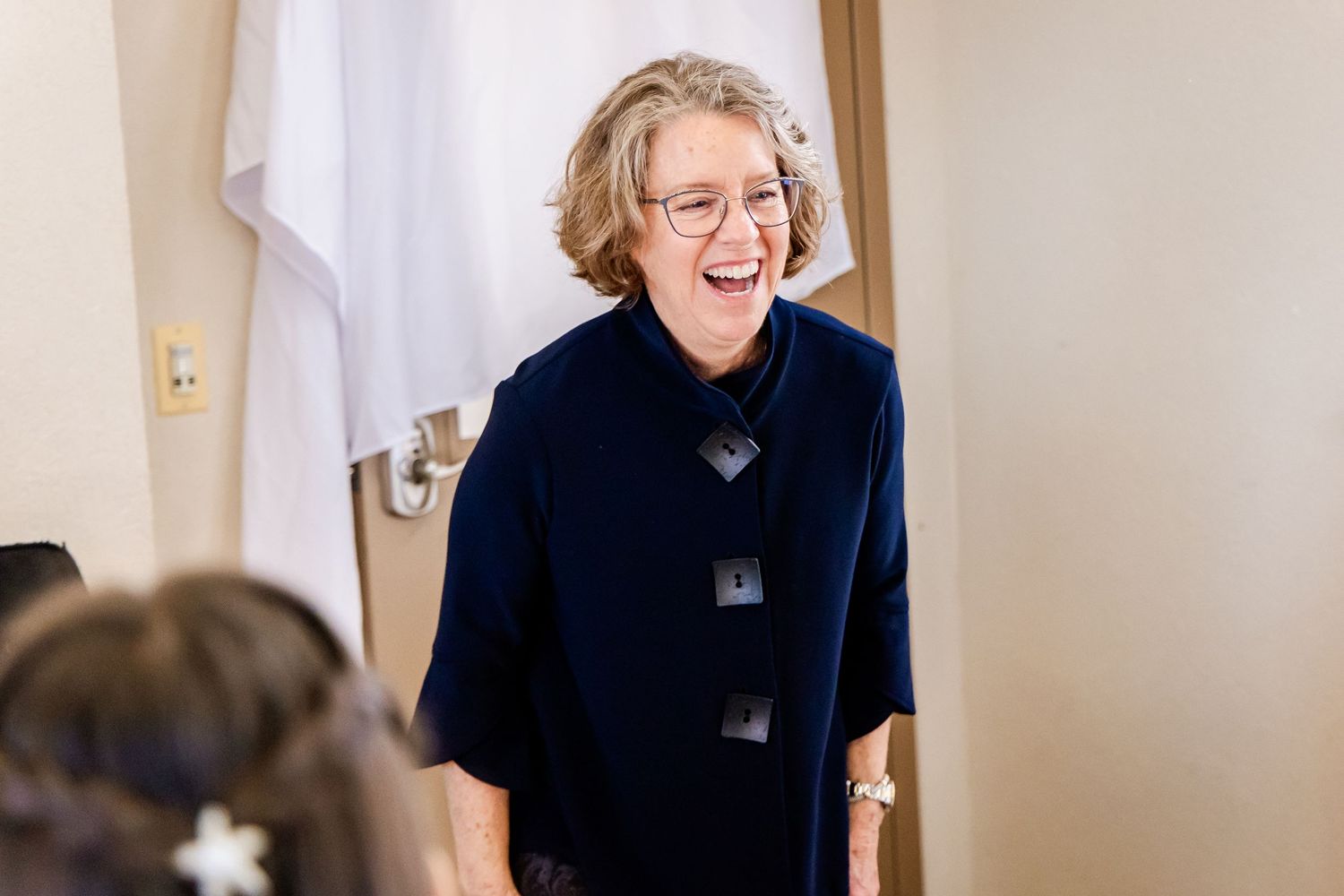 Wedding preparation moment captured with joyful expression in indoor setting.
