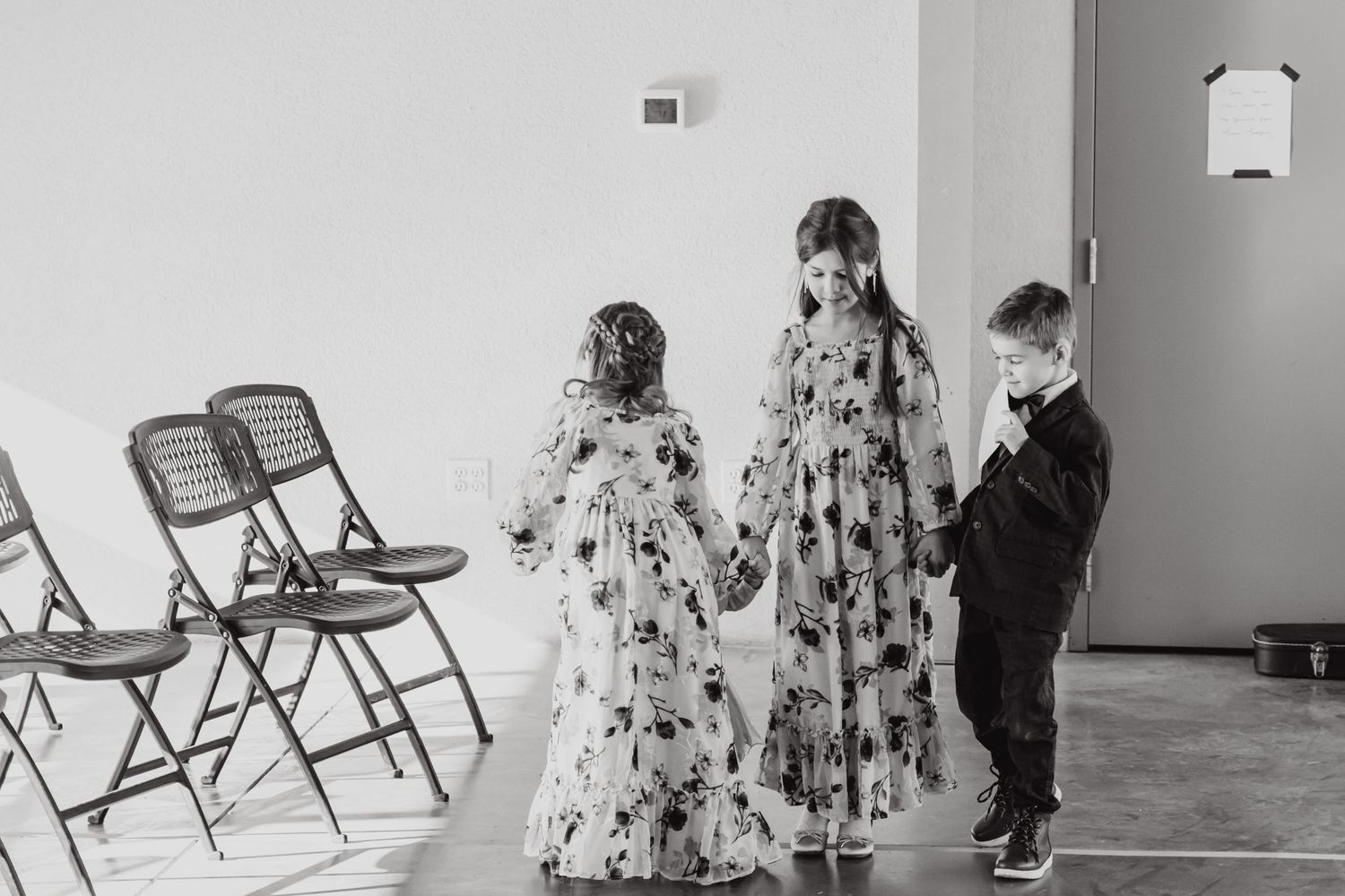 Children in floral dresses and formal wear play together in reception venue.