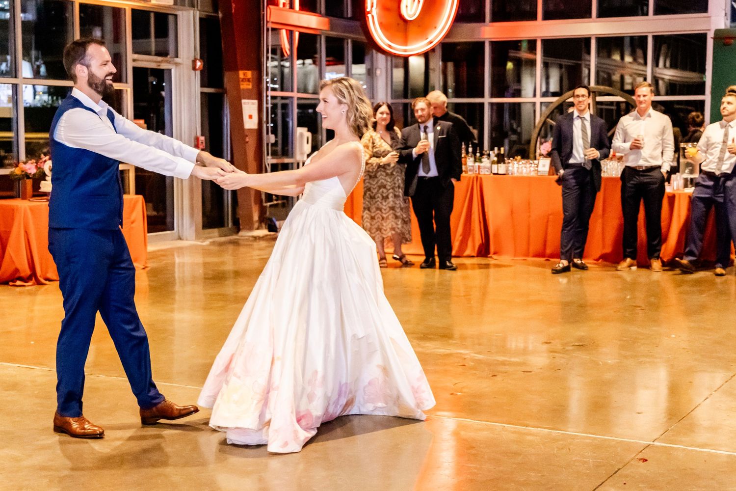 Couple performs their first dance on a polished floor at their wedding reception.