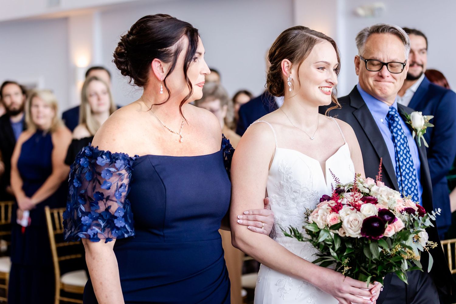 Wedding party members in navy and burgundy attire gather for celebration photos.