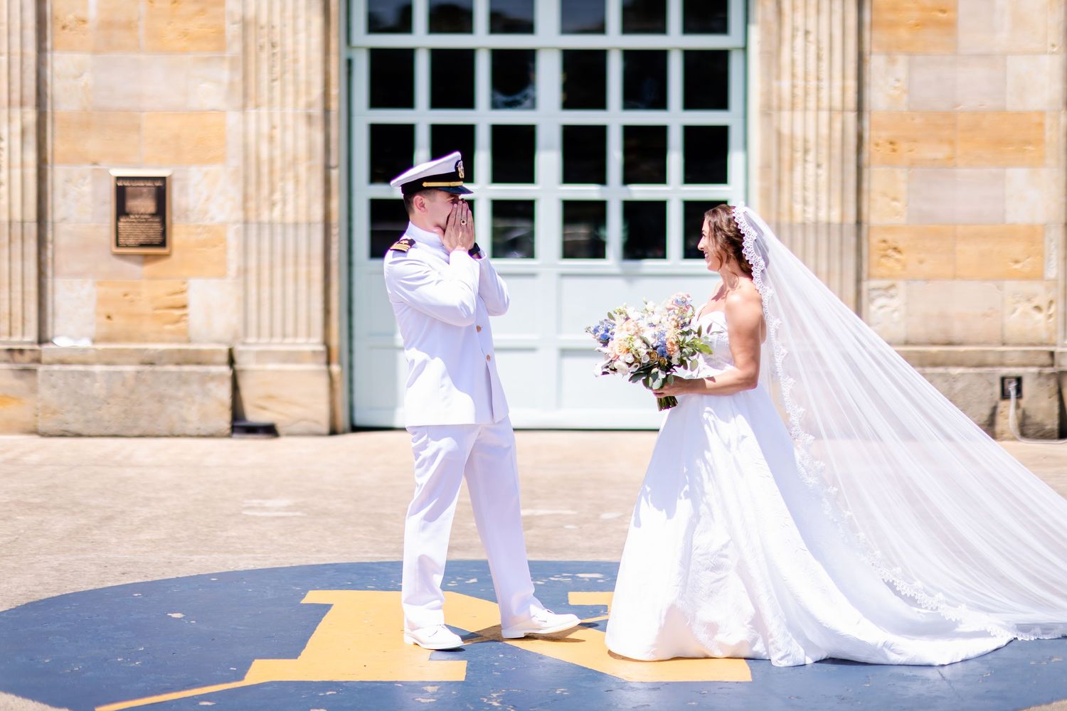 Stylish wedding party in white outfits walks together down a stone pathway outside an elegant building.