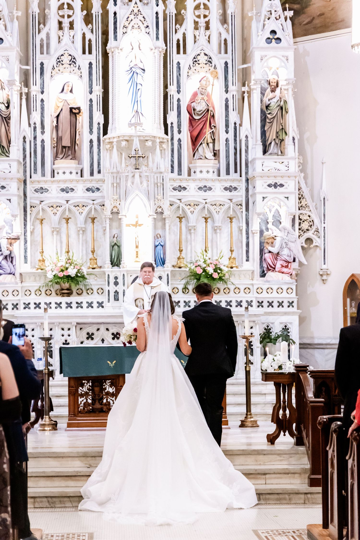 A wedding ceremony in a stunning cathedral with ornate gothic architecture and religious statues.