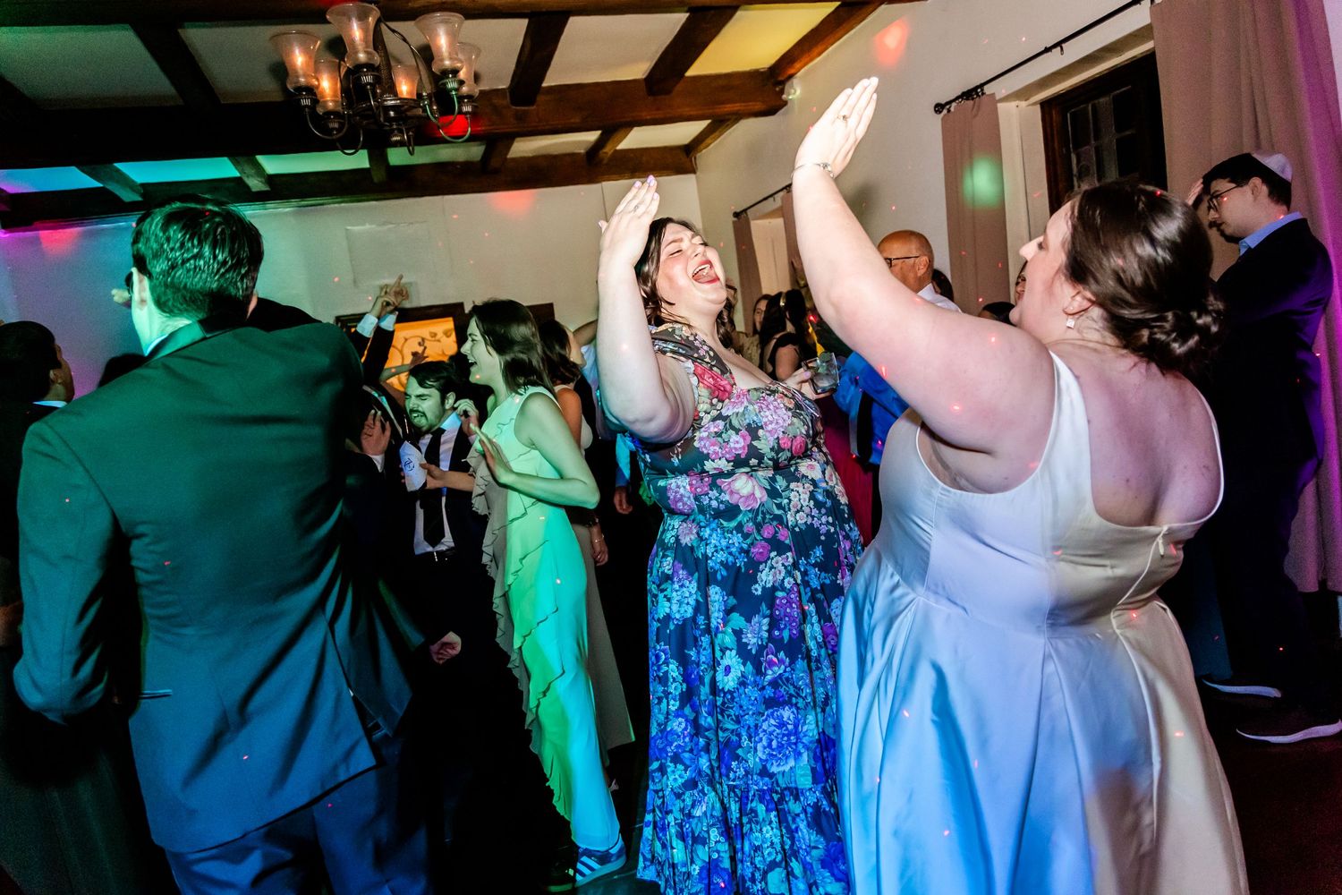 Guests dancing and celebrating at a reception with colorful party lights and elegant formal attire.