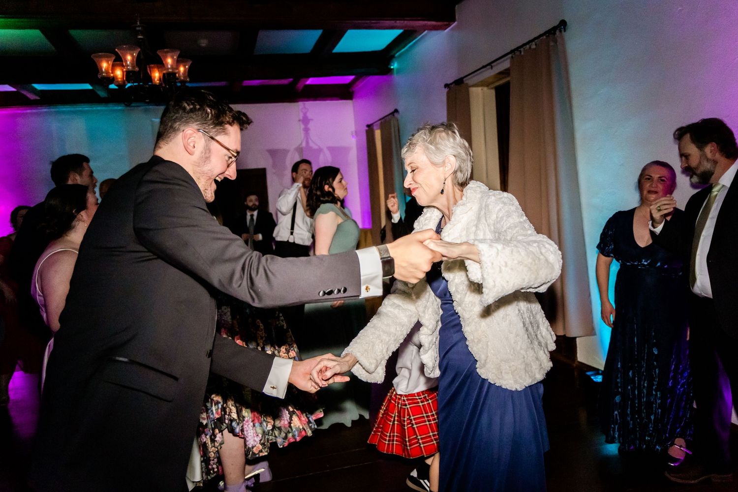 Dancing and celebration at a wedding reception with colorful purple lighting.