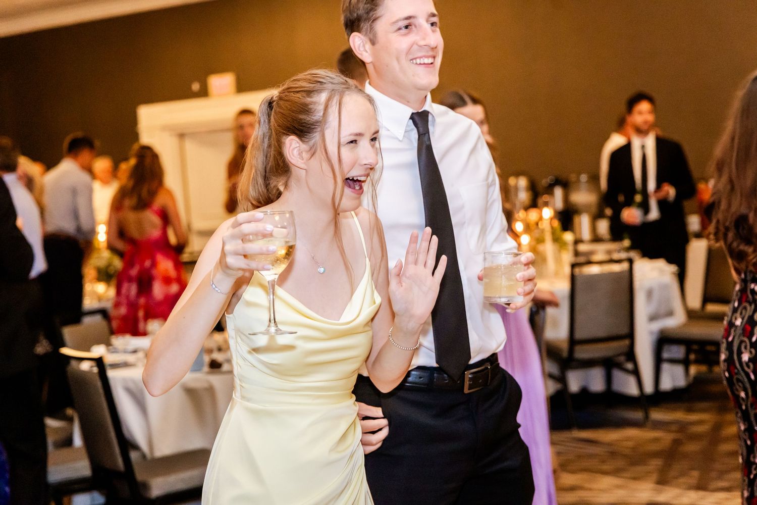 Couples dancing together during a lively wedding reception in a dimly lit ballroom.