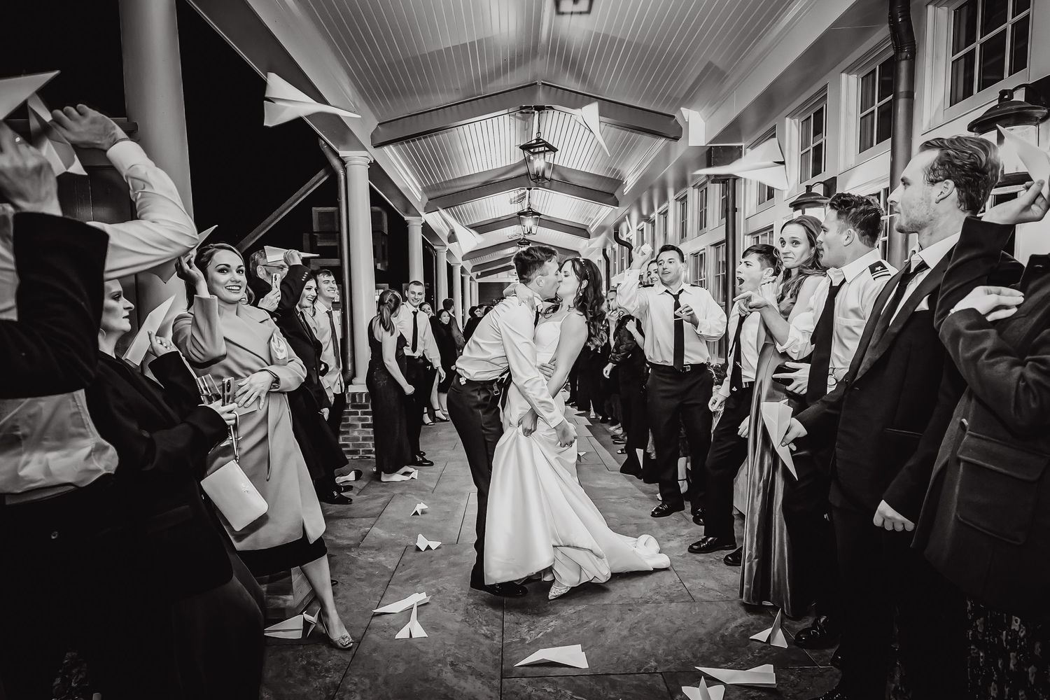 Wedding guests line both sides of a hallway creating a tunnel exit for the newlyweds during their reception celebration.