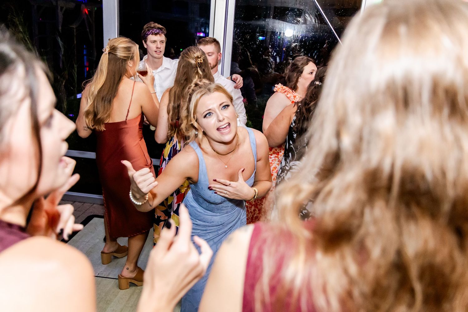Wedding guests dancing and celebrating on a dimly lit dance floor.