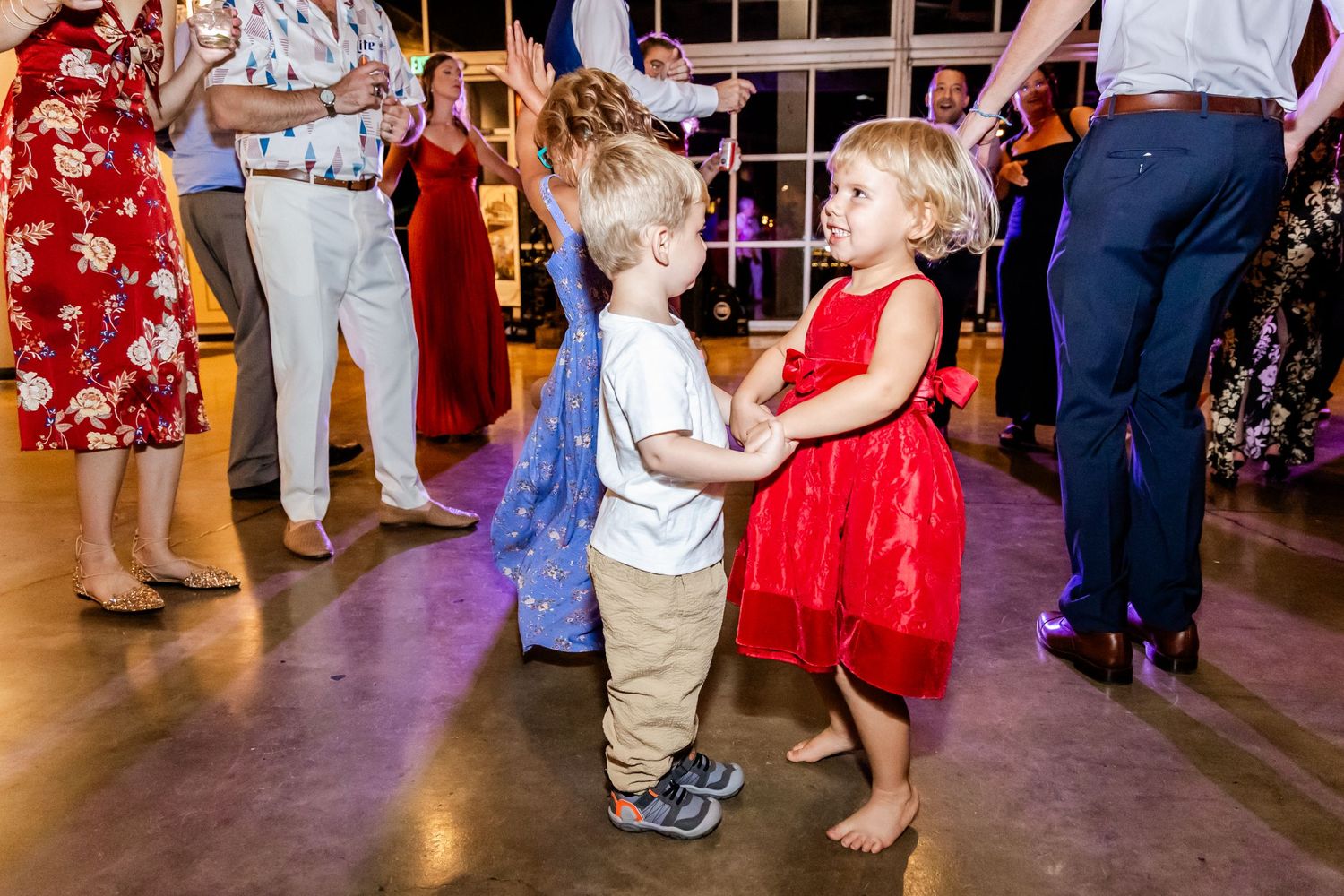 Two young children in formal wear dance together on a reception dance floor.