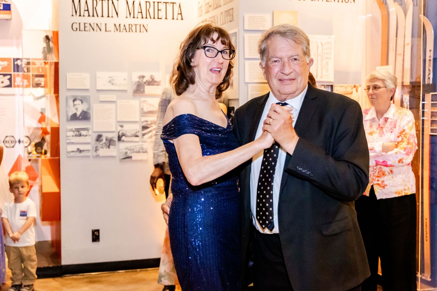 Couple dancing together at formal event with museum exhibits in background.